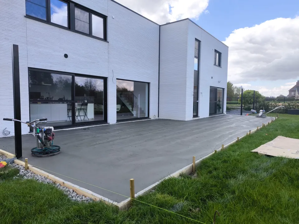Betonvloer naast een witte woning in Budingen, met een poliermachine op het oppervlak