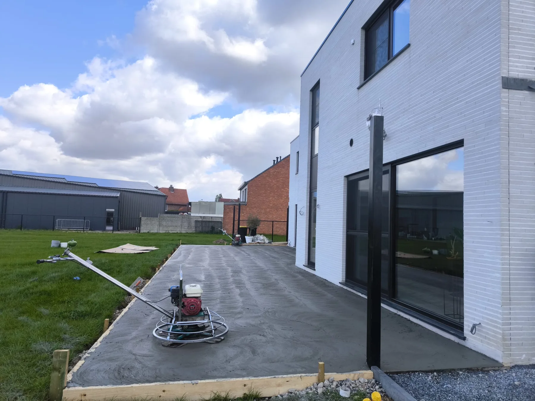 Afwerking van een gestorte betonvloer naast een woning