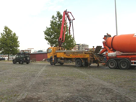 Betonmixer en betonpomp aan de kade bij de woonboot