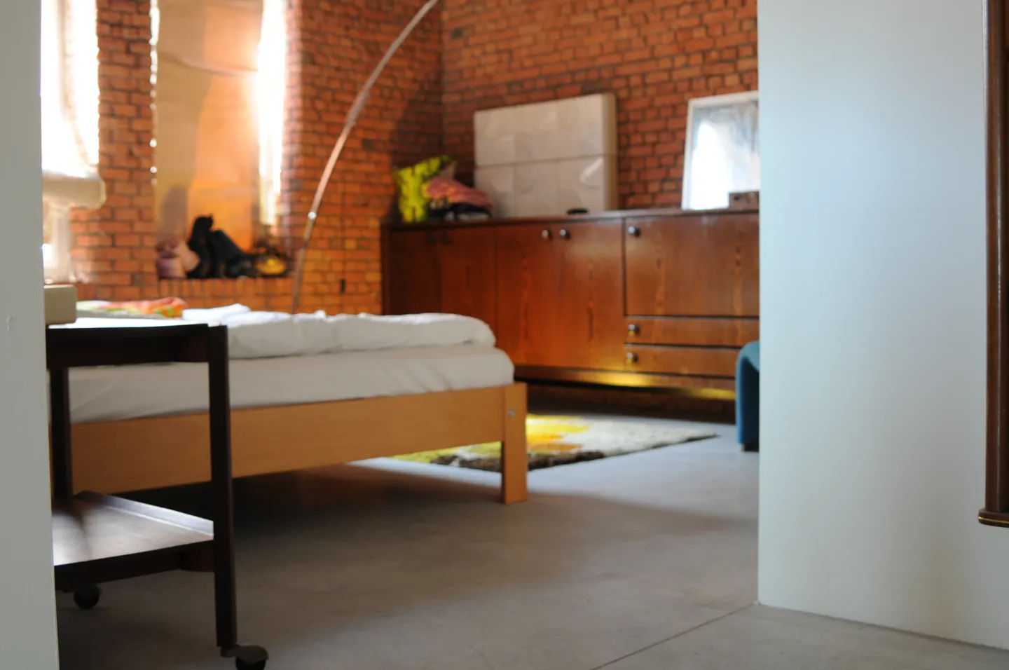 Bed en houten meubels naast de betonvloer en bakstenen wand