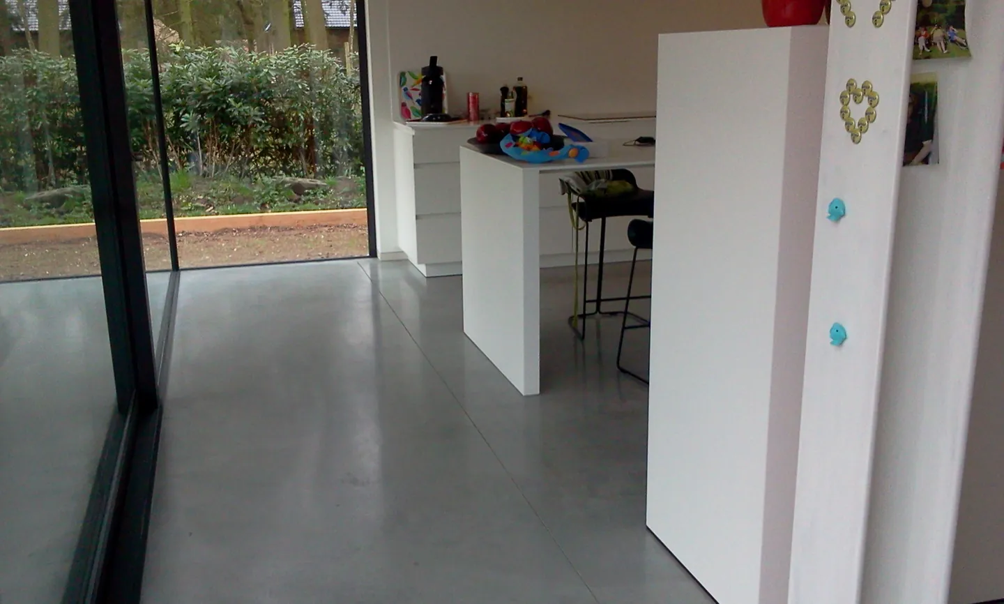 Grijze woningvloer tussen keuken en tuinraam