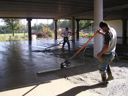 Betonvloer bij de sporthal in Maaseik wordt met een lange afwerkspaan afgewerkt