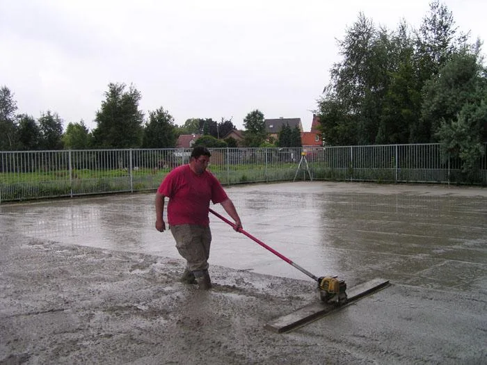 Het verse beton van de parking wordt met een brede afwerkspaan vlak gemaakt