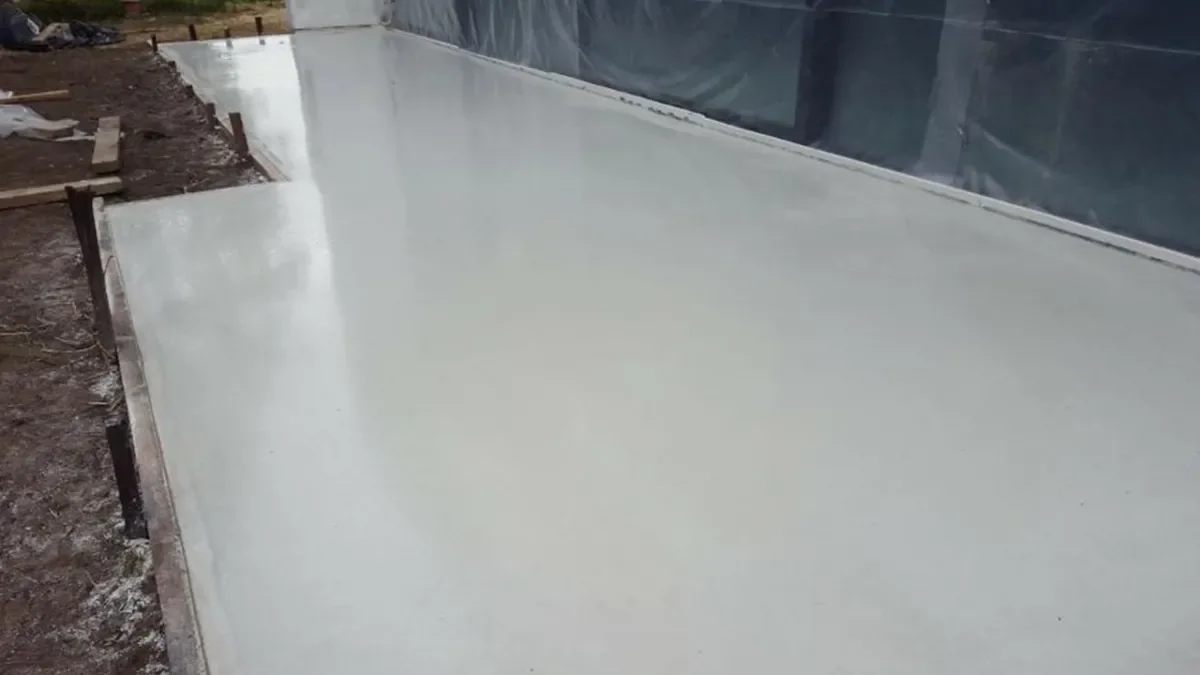 Wit betonterras in Hasselt tijdens de uitvoering, met beschermfolie langs de gevel