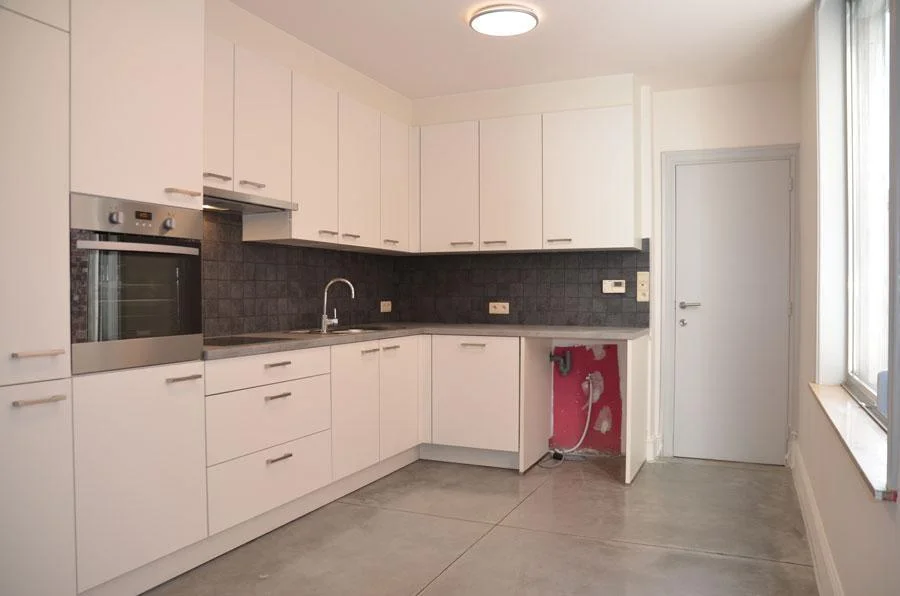 Grijze betonvloer bij de witte keuken in de rijwoning aan de Kuringersteenweg