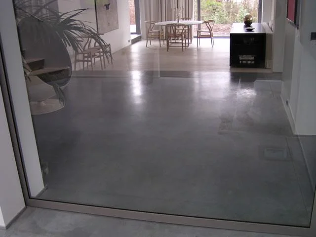 Cementkleurige betonvloer door de doorgang naar de eetruimte in Wilrijk