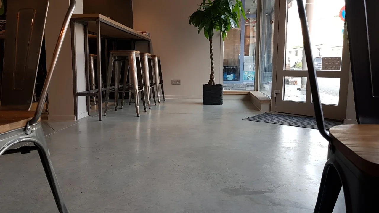 Grijze betonvloer in een interieur met houten meubels en daglicht