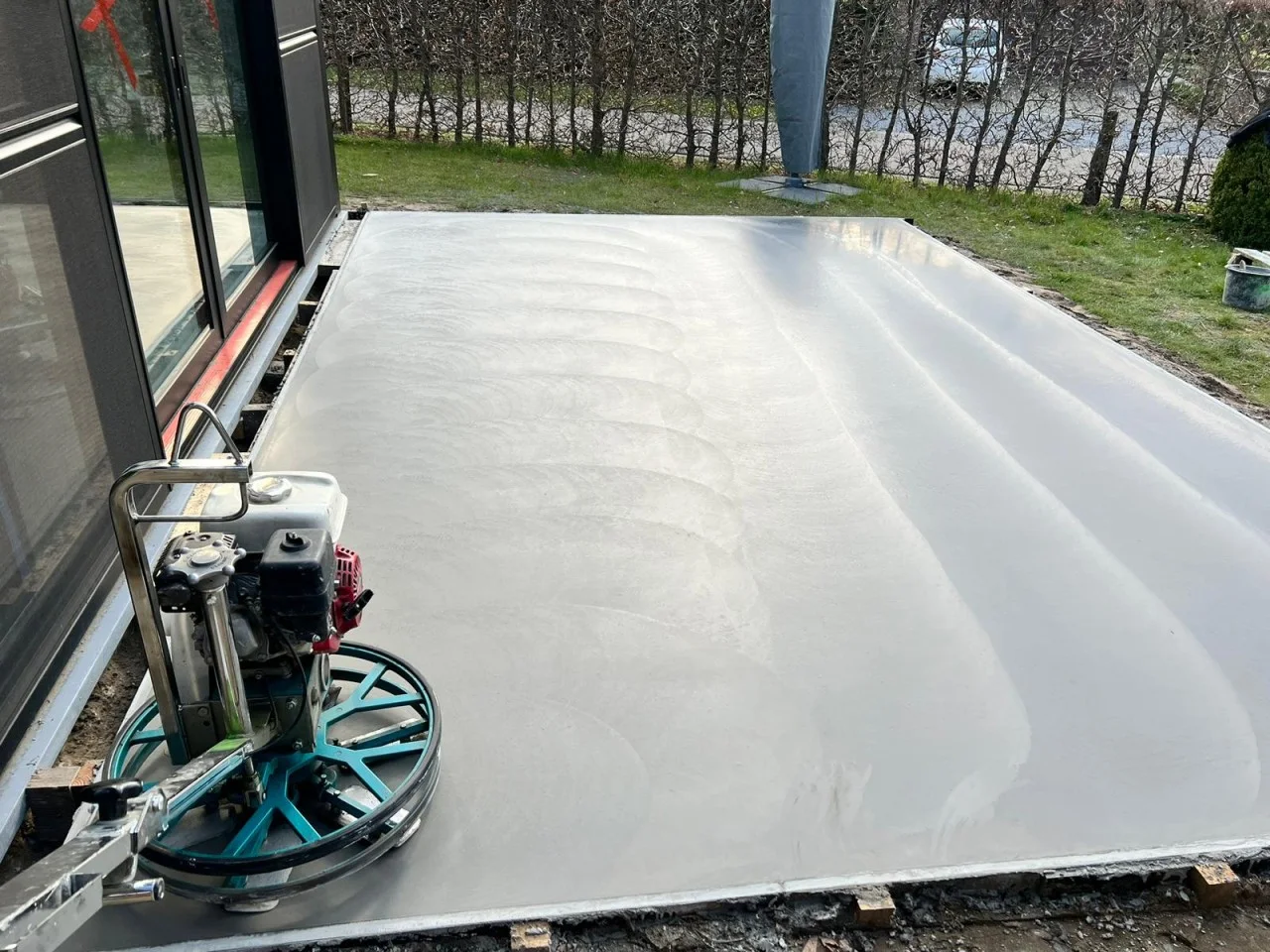 Poliermachine langs de glazen gevel bij de afwerking van een betonterras